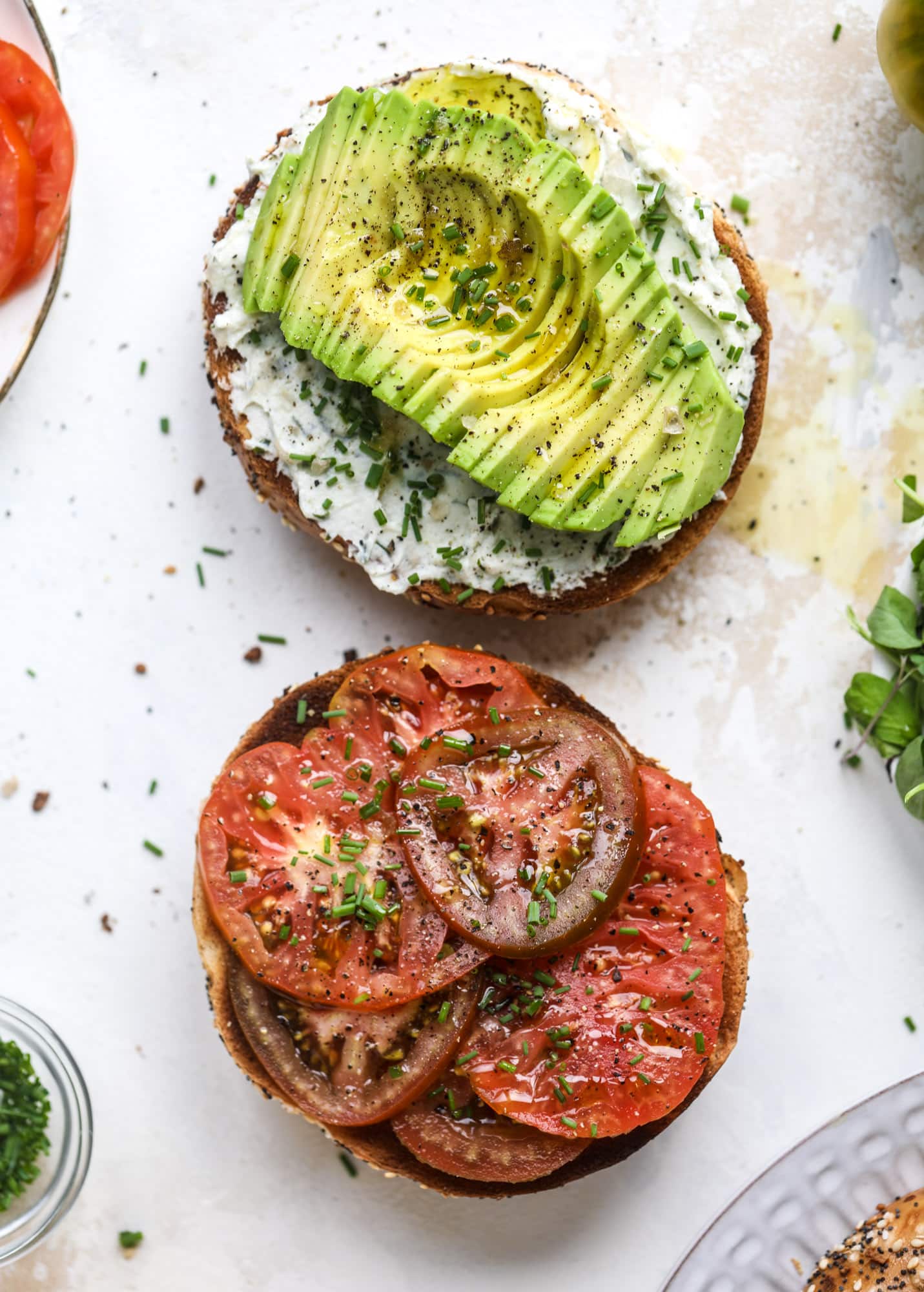 These avocado tomato sandwiches are the perfect lunch! Complete with veggie cream cheese, smoked sea salt, fresh chives and microgreens, the sliced avocado and heirloom tomatoes are sandwiched on an everything bagel for a flavor explosion. I howsweeteats.com #avocado #tomato #sandwich #healthy #lunch
