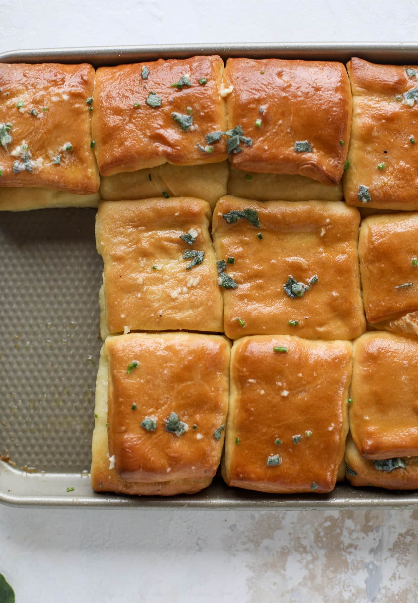 Garlic herb parker house rolls are full of incredibly buttery flavor! They are brushed with a garlic herb butter and are super fluffy, soft and tender. Perfect for Thanksgiving or the holidays and you can make the dough a bit ahead of time! I howsweeteats.com #parkerhouse #rolls