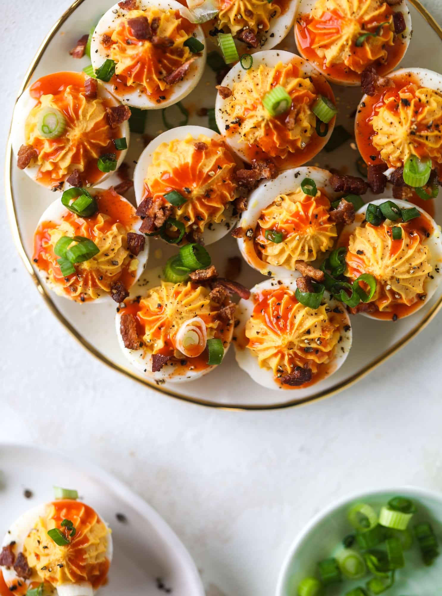 Buffalo deviled eggs are kicked-up deviled eggs! Made with goat cheese filling and served with buffalo wing sauce, crispy bacon and sliced scallions. I howsweeteats.com #deviledeggs #buffalo