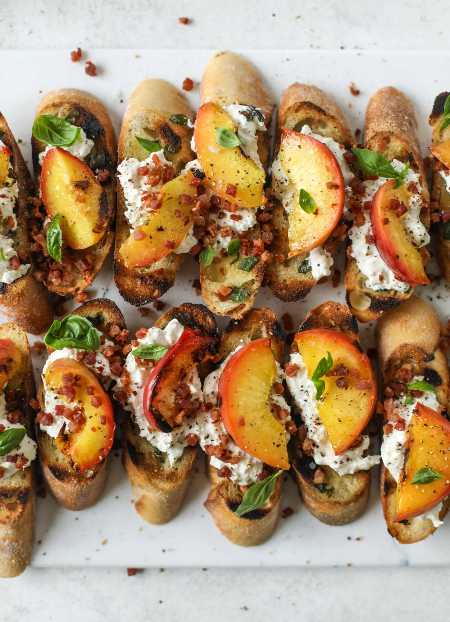 This peach burrata crostini is the best summer appetizer! it starts with grilled basil butter toasts that are topped with burrata, peach and pancetta!