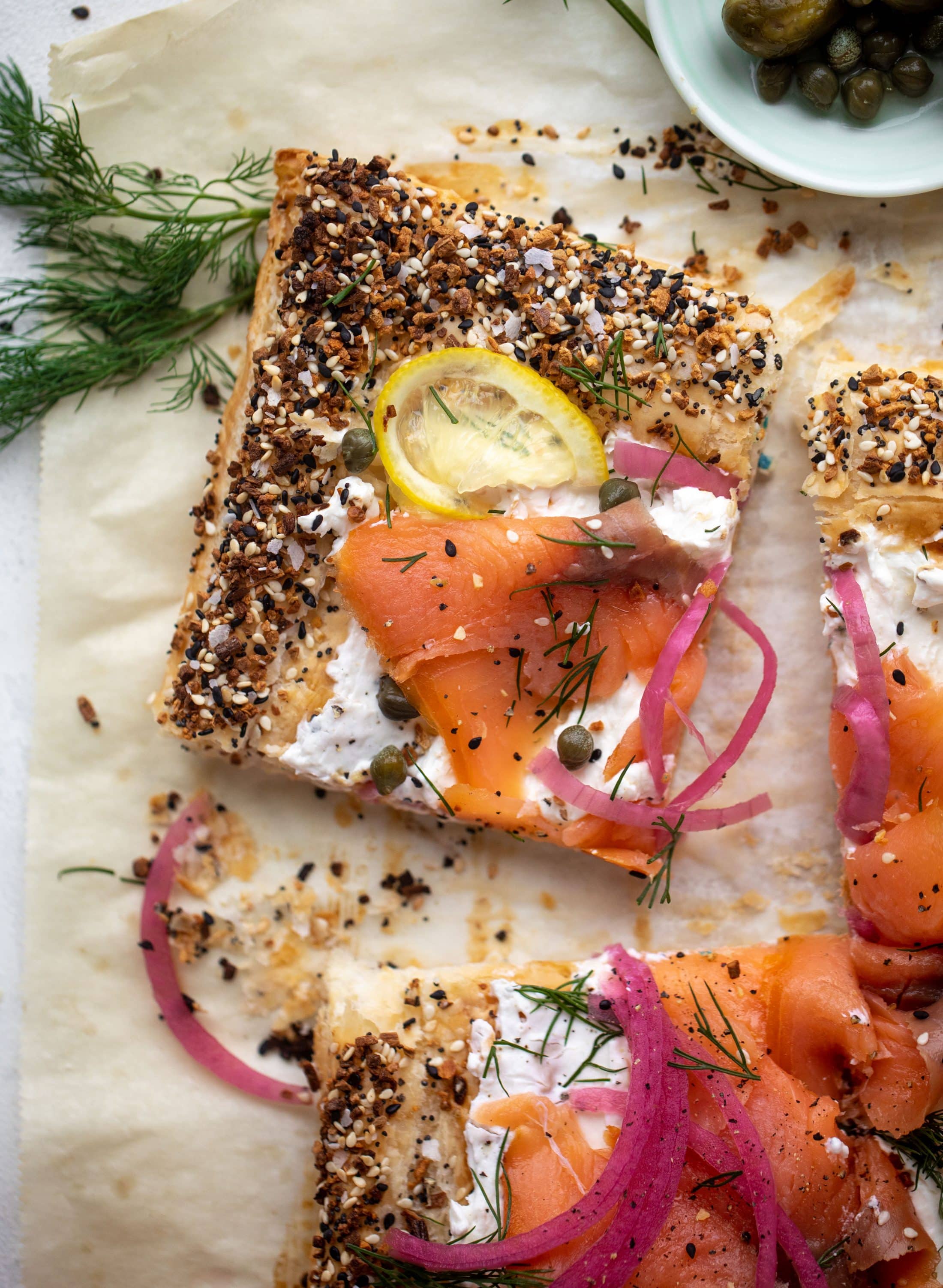 This everything smoked salmon tart is perfect for brunch! Puff pastry sprinkled with everything seasoning, slathered in cream cheese and topped with salmon.